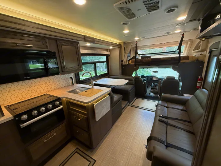 Modern rv rental interior: fully equipped kitchen, dinette, and cozy living area with sofa, ready for adventure.. Entegra Coach Odyssey 2023