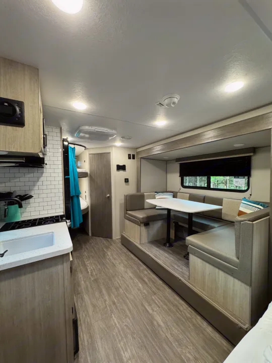 Explore this RV rental's cozy interior, featuring a well-equipped kitchen, comfortable dinette, and convenient bunk beds.. Forest River Aurora Aurora Light 2026
