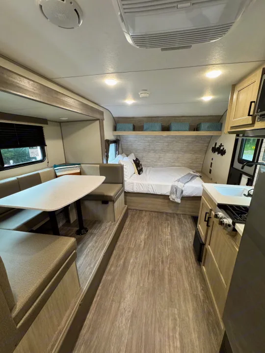 This modern rv rental camper interior features a comfy dinette, bed, and compact kitchen. Ready for your travels.. Forest River Aurora Aurora Light 2026