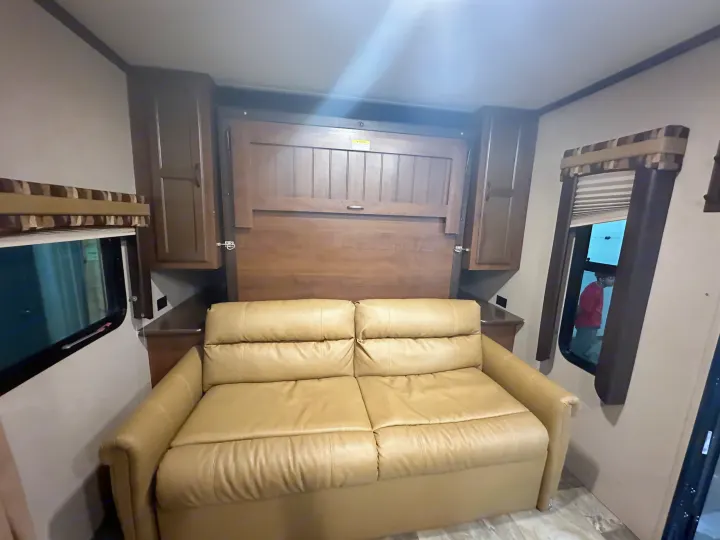 RV rental: Tan leather sofa, wooden wall bed, and cabinets create a cozy interior, perfect for comfortable travel experiences.. Jayco Jay Flight 2015