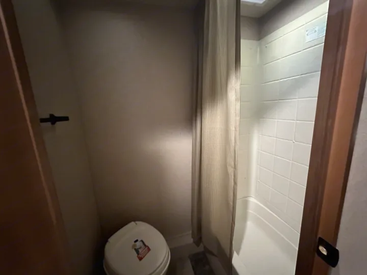 Compact RV rental bathroom featuring a small toilet and a tiled shower with a curtain for convenience.. Jayco Jay Flight 2015