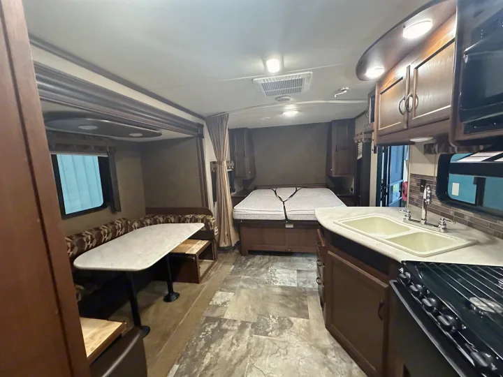 RV rental interior featuring a comfortable bed, dinette, and kitchen with sink & stove. Perfect for road trips!. Jayco Jay Flight 2015
