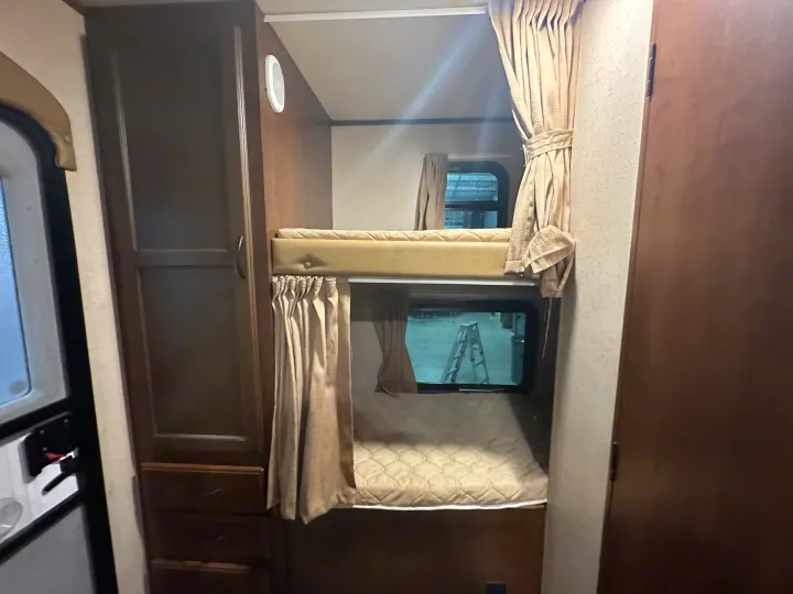 RV rental: Compact camper interior featuring comfortable bunk beds with mattresses & curtains, ideal for extra sleeping.. Jayco Jay Flight 2015