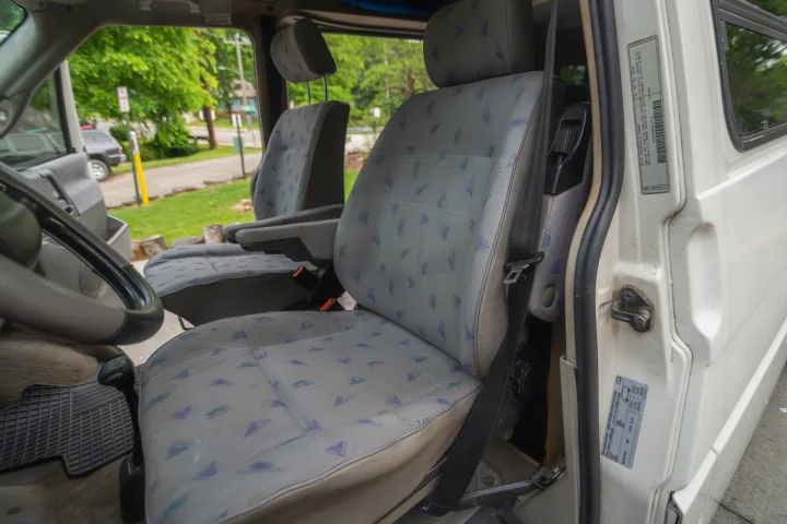 1997 VW rv rental interior: patterned front seats, steering wheel, and door jamb labels with VIN and tire pressure details.. Winnebago Eurovan Camper Eurovan Camper 1997