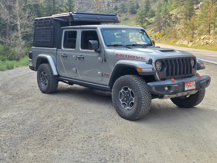 This gray Jeep Gladiator Mojave with an overland camper on a gravel road is ideal for an RV rental off-road adventure.. jeep Gladiator 2021