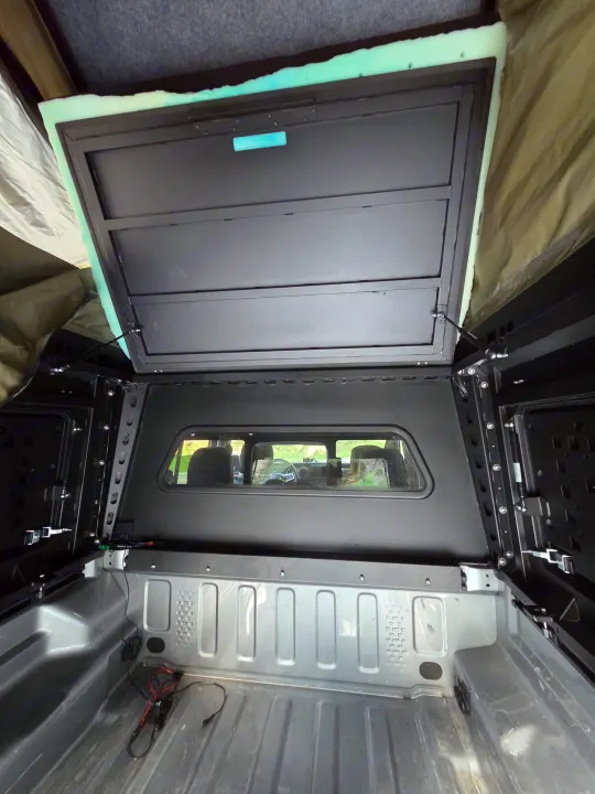 Interior view of a truck bed with an open pop-top camper, featuring a sleeping platform. Perfect for your next rv rental adventure!. jeep Gladiator 2021