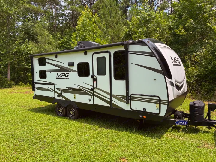 Modern 2023 MPG travel trailer, an ideal RV rental, parked on green grass with a lush forest background.. Cruiser RV MPG 2023