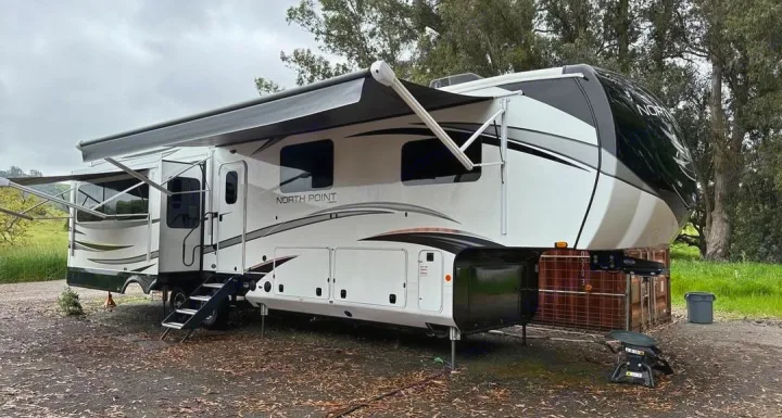 This impressive fifth-wheel RV, with its awnings extended, is parked in an outdoor setting, ready for an rv rental adventure.. Jayco North Point 2023
