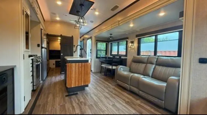 Spacious RV rental interior featuring a cozy living area with a reclining sofa, dining table, and modern kitchen.. Jayco North Point 2023