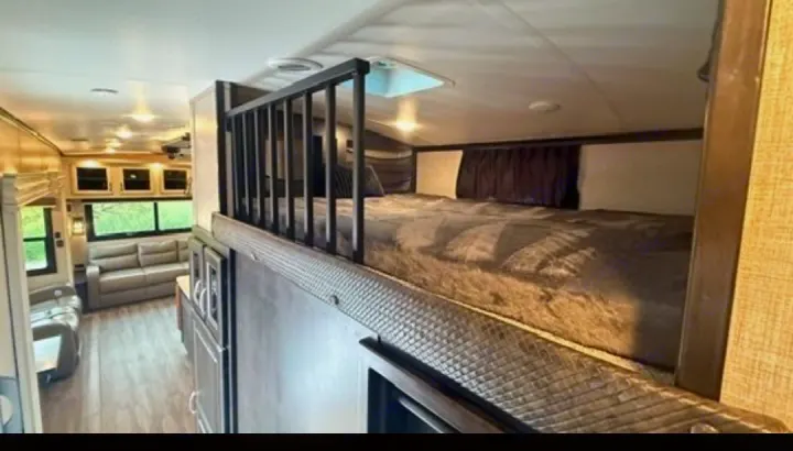 Spacious RV rental interior with a cozy loft bunk bed and comfortable living area featuring sofas and windows.. Jayco North Point 2023