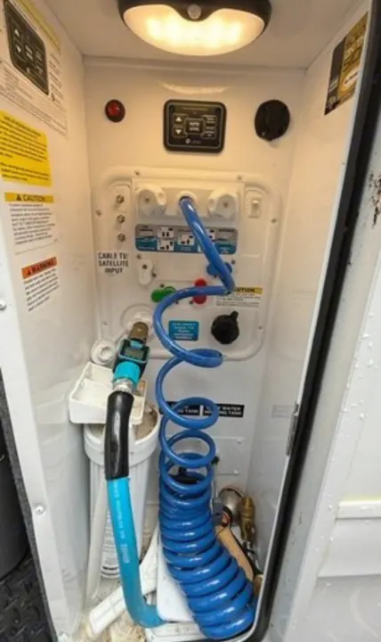 RV rental utility bay: water connections, filter, coiled hose, and shower for easy setup and maintenance.. Jayco North Point 2023