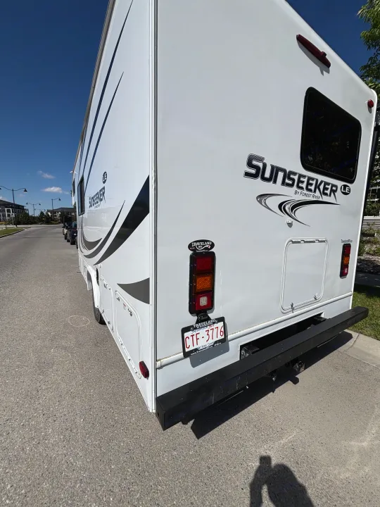 White Sunseeker RV rental parked on asphalt. A large recreational vehicle for travel and camping under a blue sky.. Forest River Sunseeker LE 2020