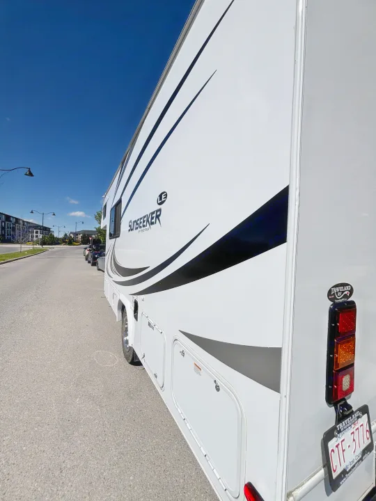 A white Sunseeker LE motorhome rv rental (CTF-3776) with black decals parked on a city street under a blue sky.. Forest River Sunseeker LE 2020
