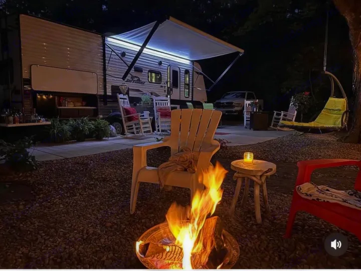 Cozy RV rental campsite at night with a warm fire pit, illuminated outdoor kitchen, and comfortable seating for a relaxing evening.. Jayco Jay Flight 2022
