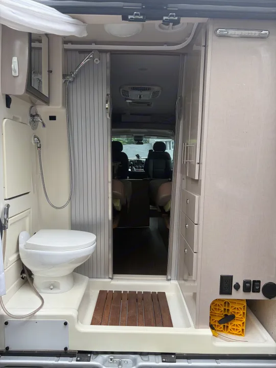 RV rental wet bath interior: compact toilet & shower. View into the camper van's cabin, highlighting space efficiency.. Winnebago Travato 2016