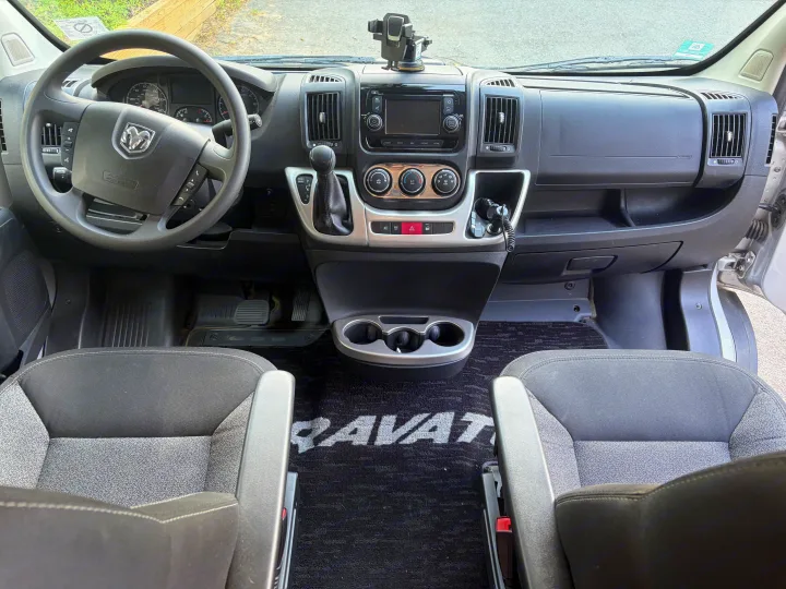 RV rental driver's view: Modern camper van cockpit with dashboard, Ram steering wheel, gear shift, and front seats.. Winnebago Travato 2016