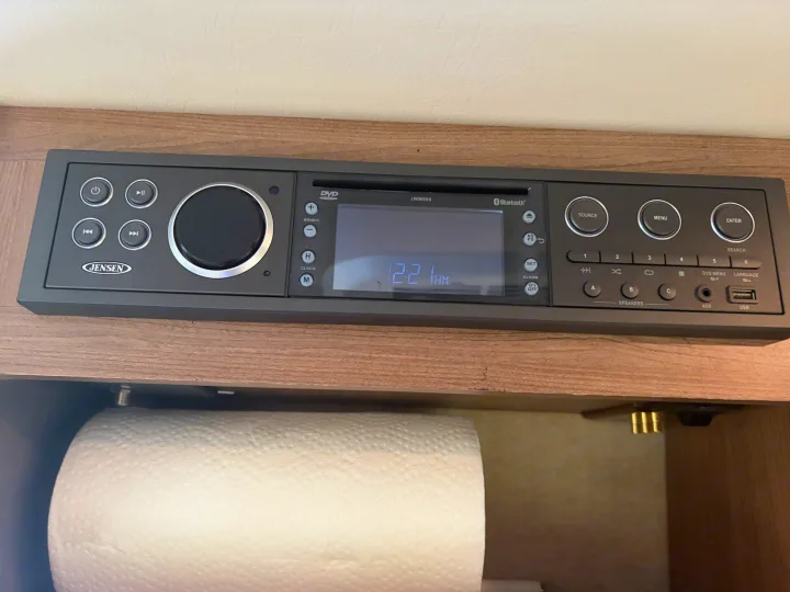 RV rental: Jensen JWM990 media console showing 12:21 AM, with DVD/Bluetooth controls, mounted above a paper towel roll.. Winnebago Travato 2016