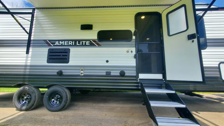 Ameri Lite RV rental showing its side, extended awning, open door with steps, and various exterior features.. Gulf Stream Ameri-Lite 2024