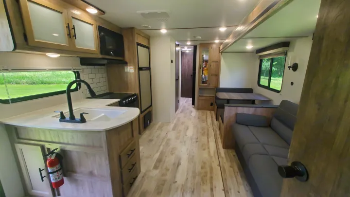 This **rv rental** showcases a compact kitchen, dinette, and sofa. Light wood tones and white walls create an inviting space.. Gulf Stream Ameri-Lite 2024