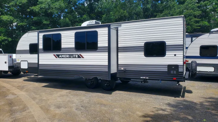 An Ameri Lite travel trailer, featuring gray and white striped siding and tinted windows, ideal for rv rental.. Gulf Stream Ameri-Lite 2024