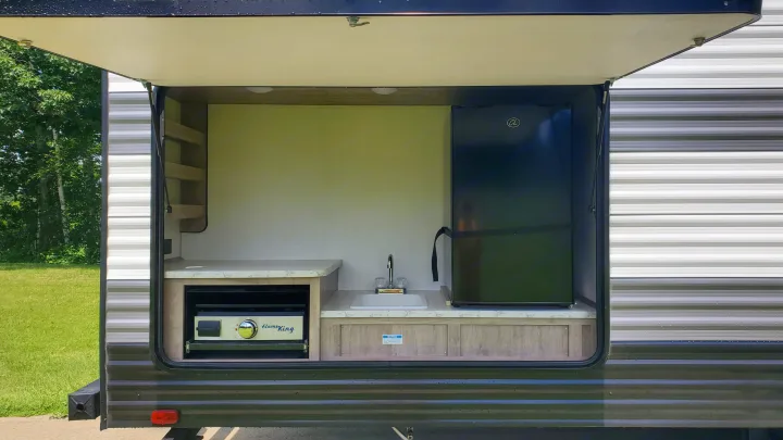 RV rental featuring an outdoor kitchen: Flame King grill, sink, mini-fridge, and shelves. Great for camping trips!. Gulf Stream Ameri-Lite 2024