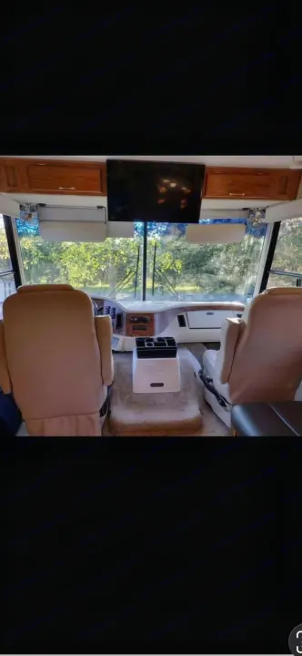 RV rental's front cabin showing driver & passenger seats, dashboard, TV, storage, and a scenic view.. Ford 1F6NF3S740A06630 2004
