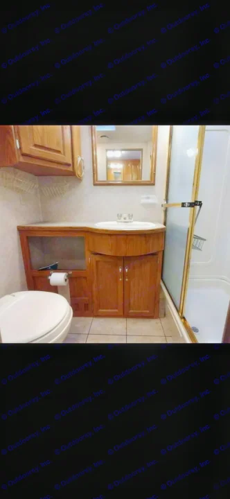Compact RV rental bathroom with wood vanity, sink, toilet, and shower stall. Perfect for on-the-road convenience.. Ford 1F6NF3S740A06630 2004