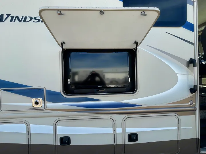 Experience an RV rental with outdoor entertainment: an open compartment reveals a mounted TV and media player on the exterior.. Thor Windsport 2019