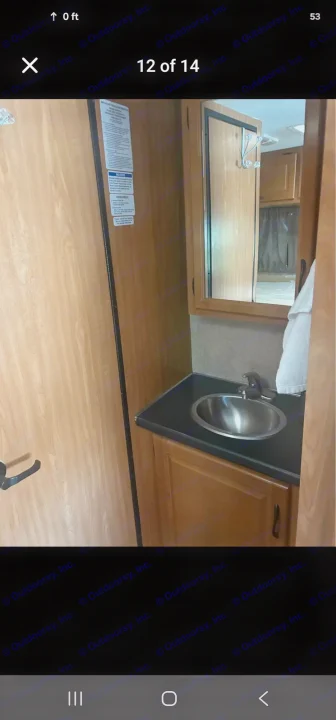 RV rental: Compact bathroom with stainless steel sink, mirror, and wood cabinetry. Important vehicle notices on wall.. Thor Majestic 2017