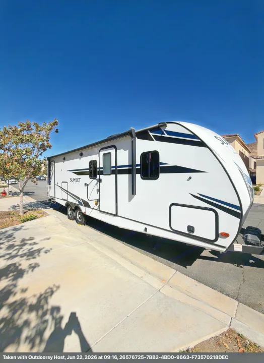A white Sunset Trail RV rental travel trailer with black accents, parked on a sunny street.. Crossroads RV Sunset Trail Super Lite 2021