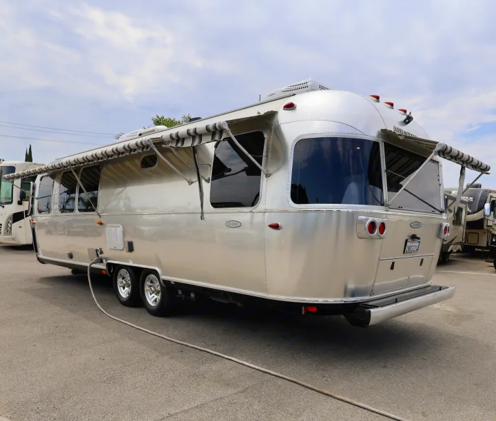 Shiny Airstream Classic travel trailer with extended awnings, potentially an rv rental, parked on asphalt outdoors.. Airstream Classic 2019