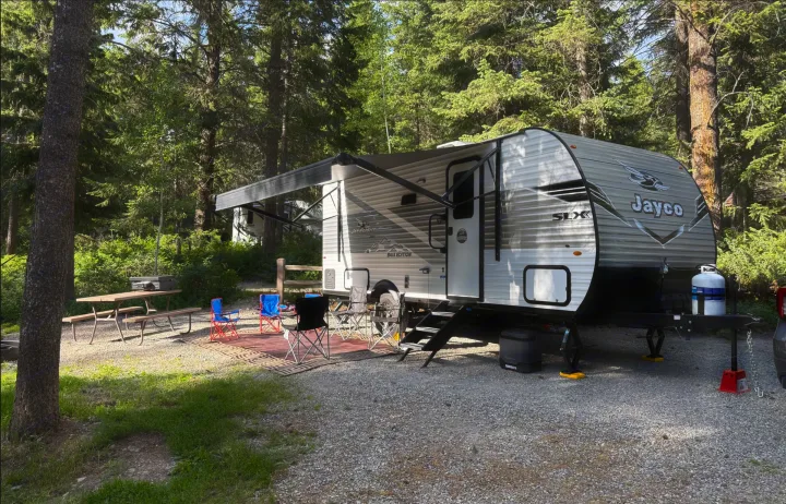 Jayco RV rental set up at a shaded campsite, complete with awning, chairs, and picnic table.. Jayco Jay Flight SLX Baja Edition 2025