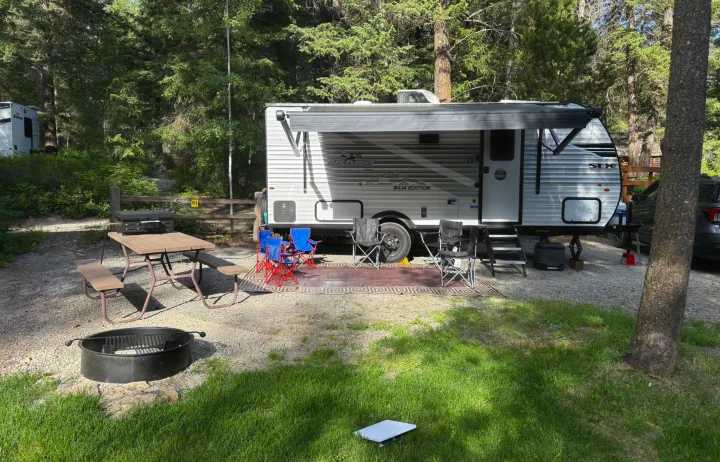 Ready for adventure! This Jayco RV rental camper is perfectly parked in a wooded campsite with a picnic table and fire pit.. Jayco Jay Flight SLX Baja Edition 2025