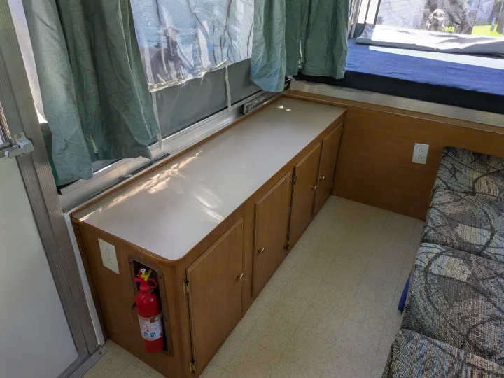 Explore this rv rental's organized interior, featuring storage cabinets, a bed, and safety essentials like a fire extinguisher.. Coleman Destiny Sedona 2002