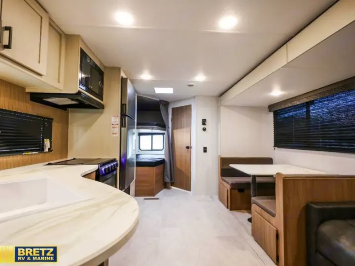 Modern rv rental interior: bright kitchen with sink & stove, comfortable dinette, and cozy bunk beds.. Keystone RV Other 2026