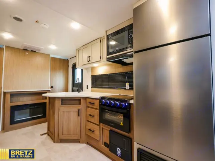 Spacious RV rental interior featuring a modern kitchen with stainless steel appliances, ample storage, and a cozy electric fireplace.. Keystone RV Other 2026