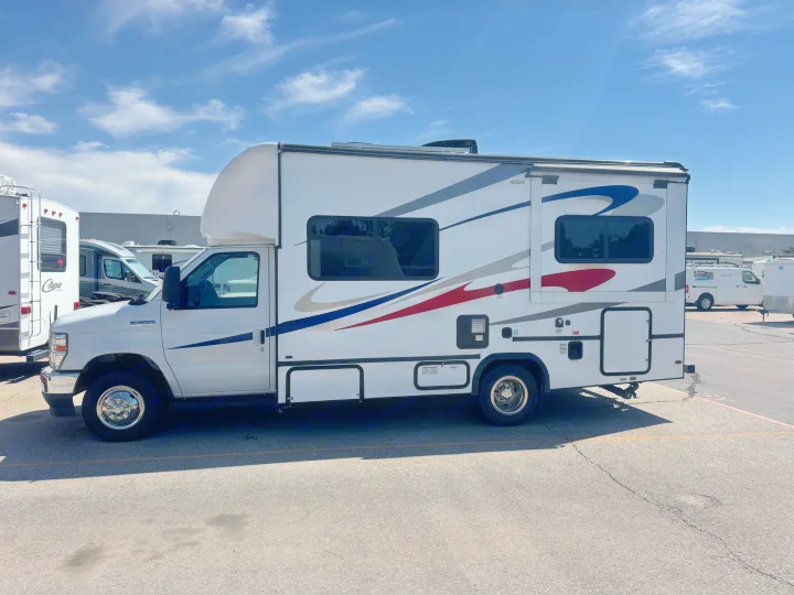 White Class C rv rental with colorful decals on the side, parked in a lot under a blue sky.. Forester Other 2023