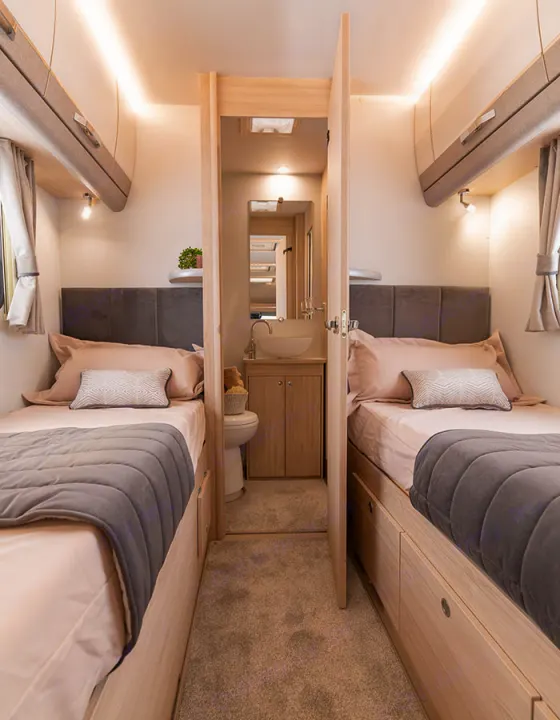 Compact RV rental interior featuring twin beds flanking a central aisle with an en-suite bathroom at the end.. Elddis Whirlwind GT 185 2026