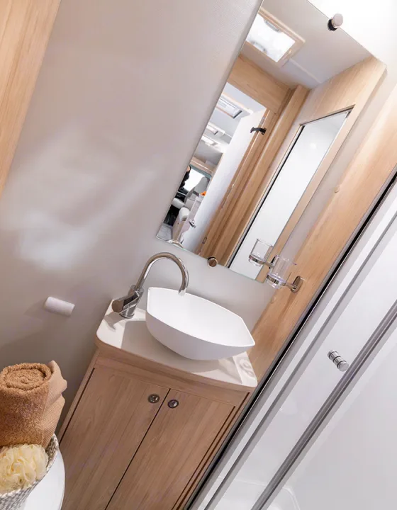 Modern RV rental bathroom: sleek sink, wood vanity, mirror, shower, and fresh towels for comfortable travel adventures.. Elddis Whirlwind GT 185 2026