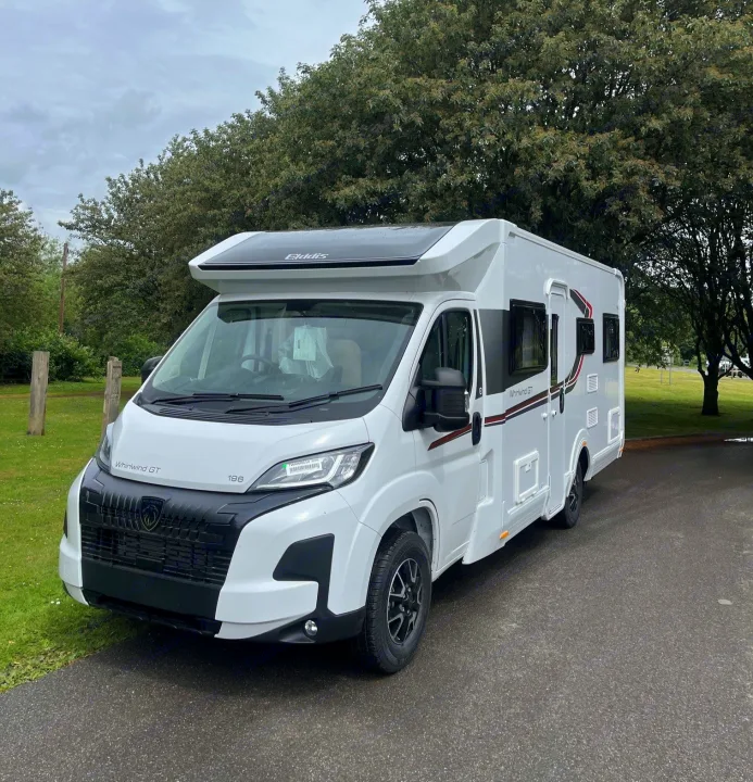 This white Elddis Whirlwind GT motorhome, perfect for an RV rental, is parked near trees on an overcast day.. Elddis Whirlwind GT 196 2026