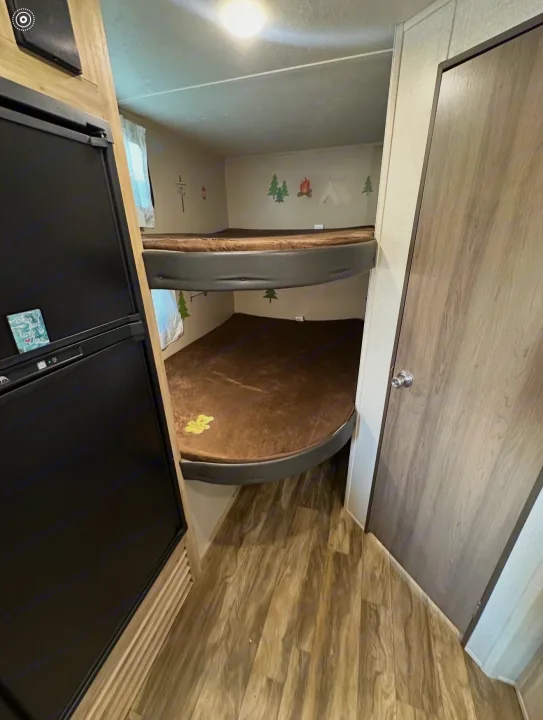 RV rental bunk beds with brown mats and playful camping decals. A black refrigerator is on the left, perfect for family adventures.. Coachmen 5ZT2CALB9LU036851 2020