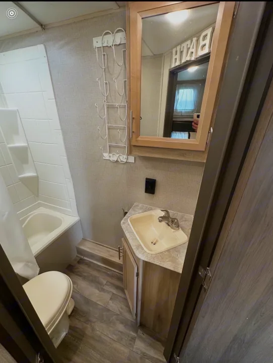 This compact RV rental bathroom features a tub/shower combo, toilet, and vanity sink, complete with a mirror.. Coachmen 5ZT2CALB9LU036851 2020