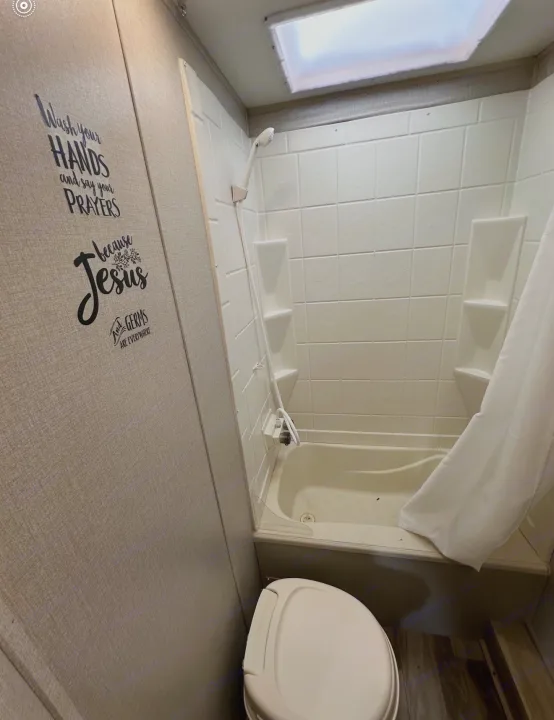 Compact RV rental bathroom featuring a toilet, shower, and a humorous "Wash your hands and pray" decal on the wall.. Coachmen 5ZT2CALB9LU036851 2020