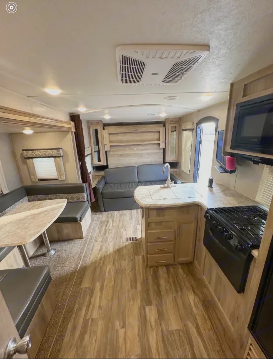 This rv rental features a combined living, dining, and kitchen space, offering a sofa, booth seating, and modern appliances.. Coachmen 5ZT2CALB9LU036851 2020