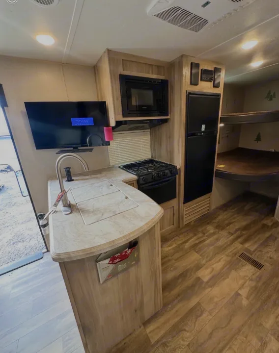 Inside a comfortable rv rental: Kitchenette with sink, stove, microwave, TV, and rear bunk beds for family travel.. Coachmen 5ZT2CALB9LU036851 2020