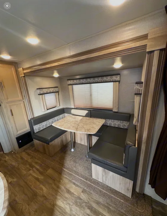 Spacious rv rental dinette features U-shaped seating, marble-look table, windows, and wood-toned cabinets. Cozy interior.. Coachmen 5ZT2CALB9LU036851 2020