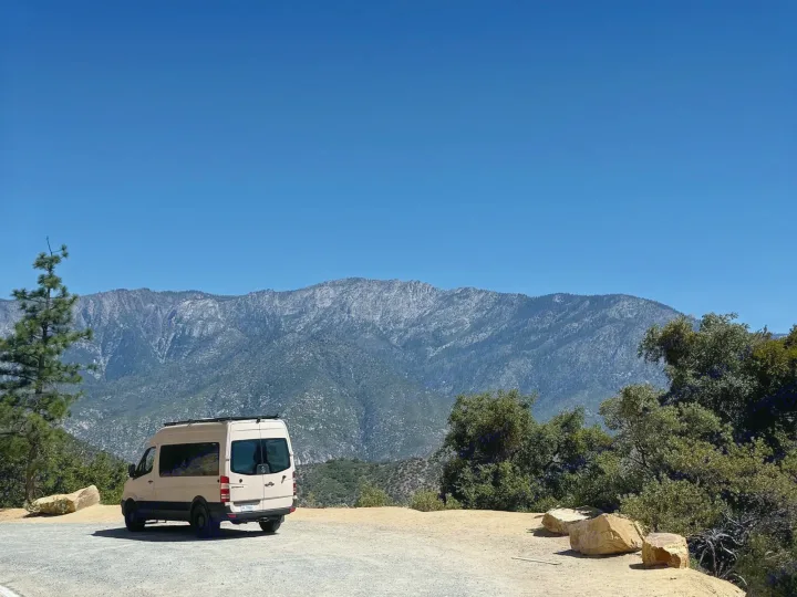 Discover breathtaking mountain views with this beige Sprinter van rv rental. Parked under a clear sky, ready for adventure.. Mercedes-Benz Sprinter 2008