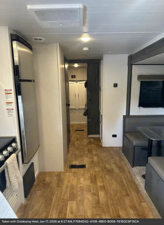 Bright RV rental interior featuring kitchen appliances, a cozy dinette, and a central hallway. Perfect for travel!. Keystone RV Hideout 2022