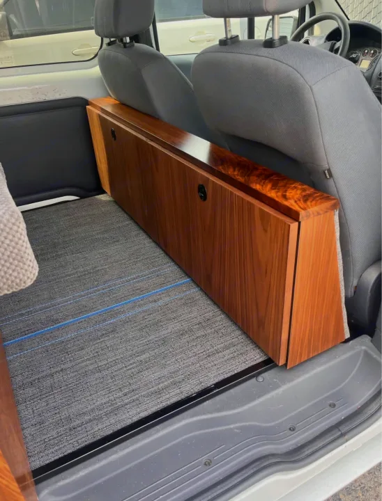 RV rental camper van interior featuring a long, custom-built wooden storage unit behind the gray front seats on carpeted floor.. Ford Transit 2013
