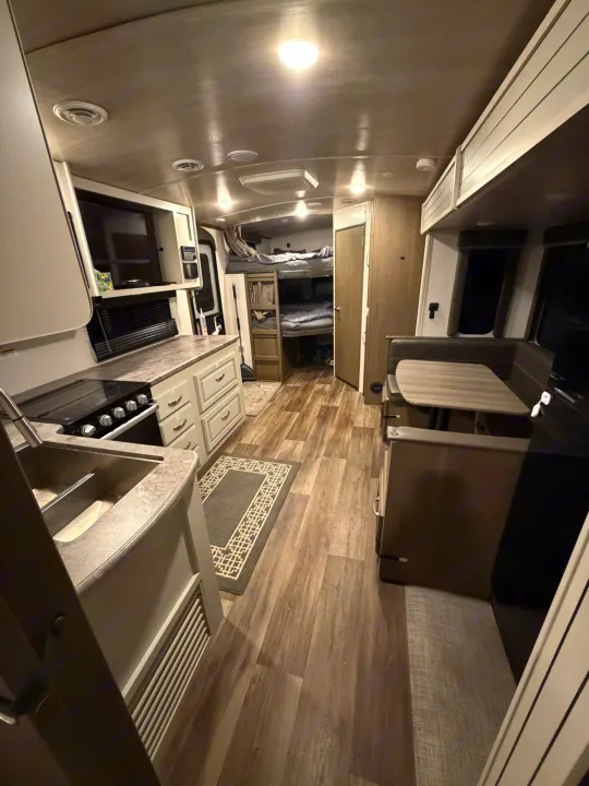 Spacious RV rental interior featuring a kitchen, dinette, and bunk beds, perfect for family travel.. Keystone RV Cougar 2023